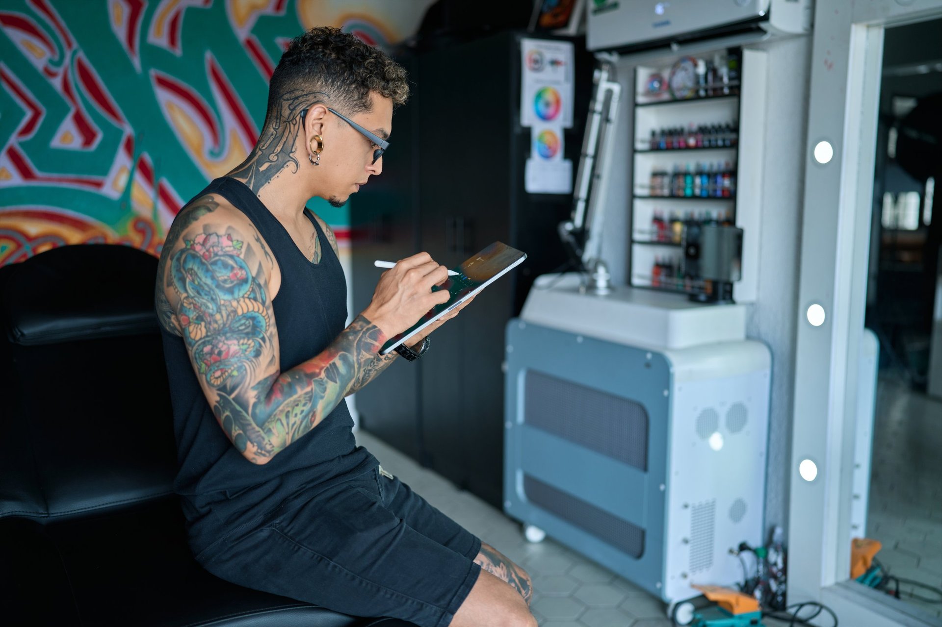 Tattoo professional sketching intricate design on digital tablet, working in sleek creative workspace with advanced drawing tools